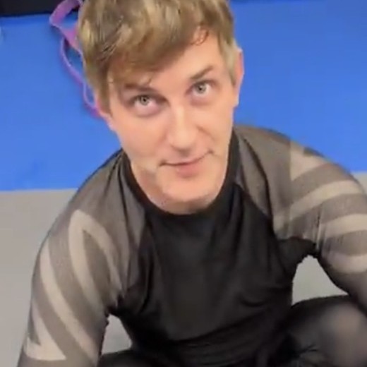 Aaron sitting on the mats in a rashguard