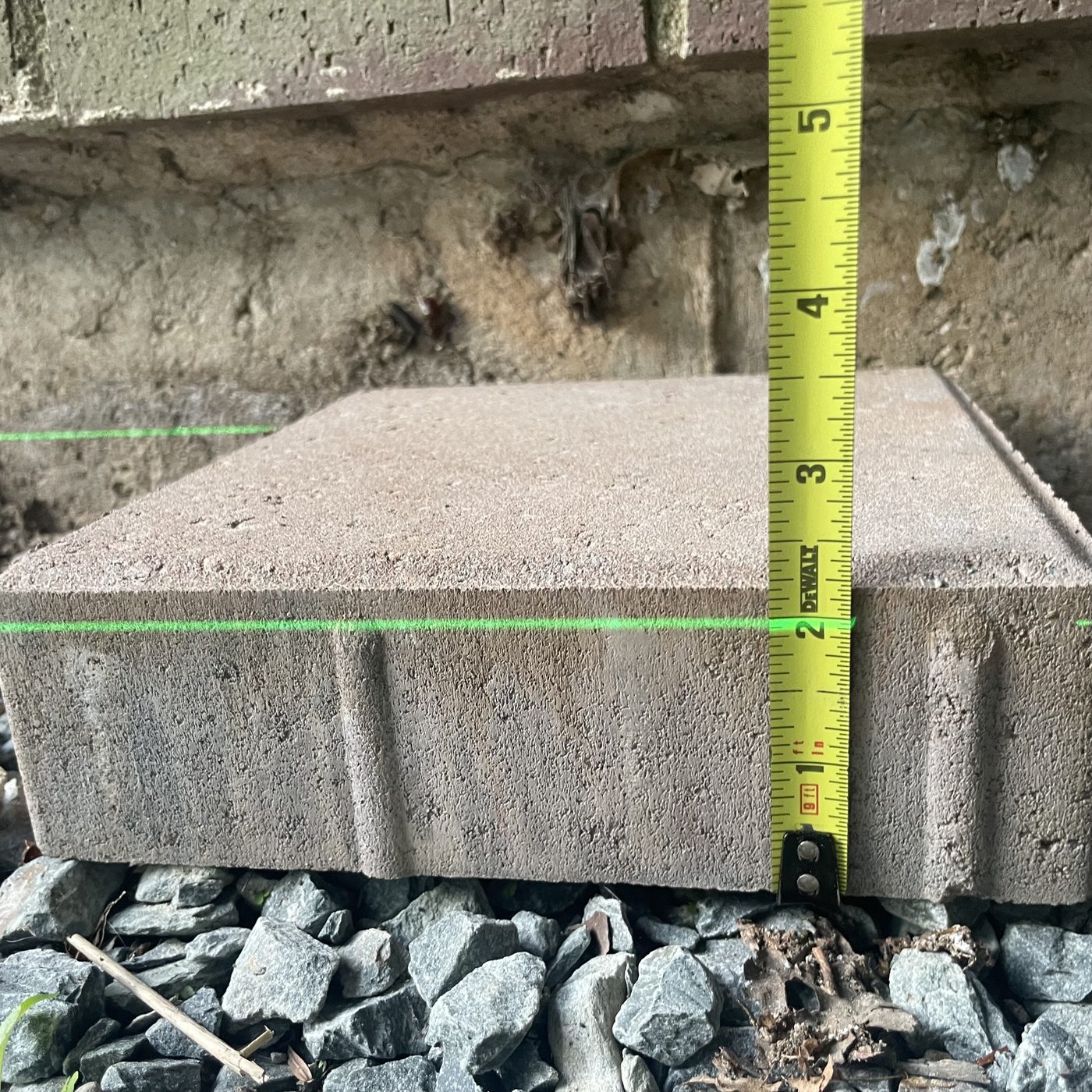 Tape measure against a paver with a green laser line across it
